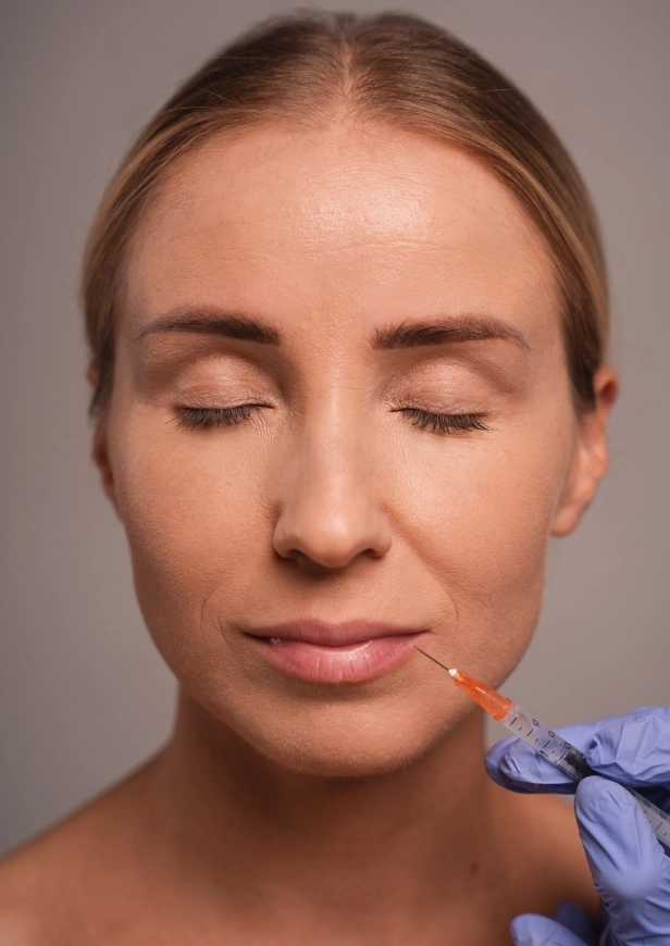 Gemini ha dicho Una mujer con los ojos cerrados recibe una inyección estética en el labio por parte de un profesional con guantes.